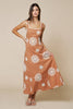 Woman wearing a caramel brown dress with white floral patterns on a beige background