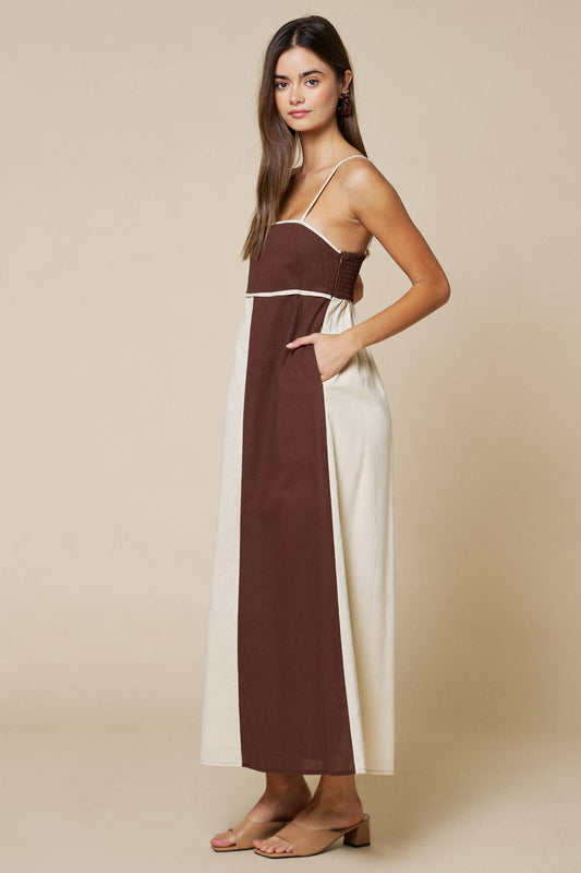Woman wearing a brown and white dress against a beige background