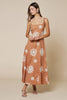 Woman wearing a caramel brown dress with white floral patterns on a beige background