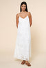 Woman wearing a white eyelet lace dress against a beige background
