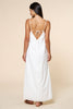 Woman wearing a white slip dress with thin straps on a beige background