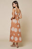 Woman wearing a long, patterned dress with a beige background